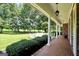 Charming covered porch with brick floor and white columns, offering a serene view of the landscaped front yard at 234 Crumbley Rd, Mcdonough, GA 30252