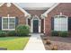 Inviting red brick home with a black front door and manicured bushes and flowers at 1032 Shumard Ln, Mcdonough, GA 30252