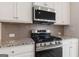 Modern kitchen with stainless steel gas range, microwave and sleek backsplash at 4464 Eastbrook Pl # 56B, Snellville, GA 30039