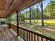 View from the covered front porch looking out towards mature trees and a grassy yard at 1000 Coan Dr, Locust Grove, GA 30248