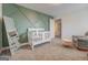A calming Bedroom featuring green wall accent, a crib, and a comfortable glider at 116 Sophie Cir, Locust Grove, GA 30248