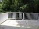 Outdoor wooden deck with white railing overlooking the lush greenery at 2498 Robinhood Dr, Ellenwood, GA 30294