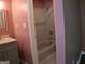 View of a shower-tub combo with tile surround, inside a full bathroom with pink walls and modern fixtures at 2498 Robinhood Dr, Ellenwood, GA 30294