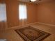 Bright bedroom featuring a large window with white curtains, beige walls and decorative rug at 2498 Robinhood Dr, Ellenwood, GA 30294