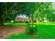 A lush green backyard with mature trees and plants framing a view of the beautiful stone home at 508 College St, Bowdon, GA 30108