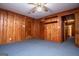 Basement features wood paneling, carpeted floors, with a ceiling fan and an open doorway at 508 College St, Bowdon, GA 30108