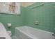 Vintage bathroom with mint green tiles, featuring a classic bathtub, adding retro charm to the space at 508 College St, Bowdon, GA 30108