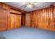 Cozy bedroom features wood paneled walls, ceiling fan and blue carpet at 508 College St, Bowdon, GA 30108