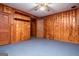 Cozy bedroom features wood paneled walls, ceiling fan and blue carpet at 508 College St, Bowdon, GA 30108