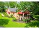 Angled view of a charming stone home featuring red awnings, trimmed shrubs, and lush green lawn at 508 College St, Bowdon, GA 30108