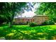 Lush green lawn with mature trees in front of the stunning stone house at 508 College St, Bowdon, GA 30108