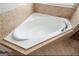 Corner bathtub with tile surround and chrome fixtures offers a relaxing retreat at 6665 Flagstone Ct # 918, Cumming, GA 30028