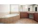 Bathroom featuring tile floors, a corner tub, granite counters and wood cabinets at 6665 Flagstone Ct # 918, Cumming, GA 30028