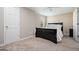 Neutral bedroom features a black bed frame, plush carpet, and white door at 6665 Flagstone Ct # 918, Cumming, GA 30028