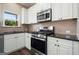 Modern kitchen with stainless steel appliances, white cabinetry, and dark countertops at 6665 Flagstone Ct # 918, Cumming, GA 30028