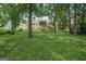 Large backyard with green grass, mature trees, and a deck at 1535 Smoke Hill Dr, Hoschton, GA 30548