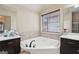 Bathroom featuring soaking tub between dark vanities, tile, and window at 2126 Roberts View Trl, Buford, GA 30519