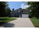 Long concrete driveway leads to a two-car garage, surrounded by a lush green lawn and mature trees at 9 Warrior Way, Sharpsburg, GA 30277