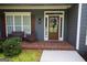 Inviting front porch with brick flooring, stylish seating, and a decorative wreath on the glass paneled front door at 9 Warrior Way, Sharpsburg, GA 30277