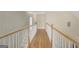 Bright hallway with wood floors, white walls and trim, and oak handrail with bedroom access at 9 Warrior Way, Sharpsburg, GA 30277
