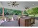 Charming covered patio with brick flooring, ceiling fans, and outdoor kitchen island at 9 Warrior Way, Sharpsburg, GA 30277