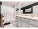 Well-lit bathroom featuring double sinks, a black accent wall, and a shower with a patterned curtain at 12167 Conrad Cir, Hampton, GA 30228