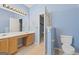 Light blue bathroom with wooden vanity, a large mirror, and a partially open door leading to another room at 377 Avian Forest Dr, Stockbridge, GA 30281