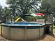 Backyard view of a pool with an attached slide and wooden patio with furniture and umbrellas at 51 Estates Dr, Villa Rica, GA 30180