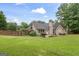 Home exterior with lush green lawn, mature trees, and patio with seating provides an outdoor living space at 200 Pine Tree Ln, Mcdonough, GA 30252