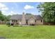 Home exterior shows a well-maintained backyard with lush lawn, mature trees, and patio with outdoor seating at 200 Pine Tree Ln, Mcdonough, GA 30252