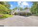 View of the home with a large covered carport, lush greenery, and an expansive driveway at 357 W Hightower Trl, Social Circle, GA 30025
