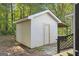 Exterior shot of a storage shed with a door and vinyl siding, nestled amongst lush trees on a beautiful lot at 340 Loblolly Rdg, Locust Grove, GA 30248