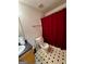 A bathroom features black and white tile, a red shower curtain, toilet and sink at 955 Foxworthy Ln, Riverdale, GA 30296