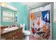 Brightly decorated bathroom featuring a vanity sink, toilet, and shower with a vibrant, patterned curtain at 207 Conkle Rd, Hampton, GA 30228