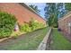 Side yard featuring brick wall, greenery, and grassy area at 286 Prominent Loop, Mcdonough, GA 30253