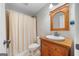 Cozy bathroom with wooden vanity, framed mirror, and a shower with a striped curtain at 5585 Lavender Farms, Powder Springs, GA 30127