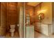 Bathroom featuring wood paneling, toilet, and double sinks at 1051 Lake Rutledge Rd, Rutledge, GA 30663