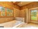 Bathroom with a large bathtub, tiled shower, and dual windows with wood trim at 1051 Lake Rutledge Rd, Rutledge, GA 30663