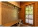 Inviting mudroom featuring wooden bench with coat hooks, a paneled wall, and a glass door that leads to the outside at 1051 Lake Rutledge Rd, Rutledge, GA 30663