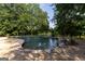 Beautiful pool with stone coping surrounded by mature trees and lush greenery, offering a serene escape at 1051 Lake Rutledge Rd, Rutledge, GA 30663