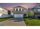 Two-story home featuring stone accents, a two-car garage, a green lawn, and neutral colored siding at 2384 Hastings Manor Ln, Hampton, GA 30228