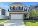 Two-story home featuring stone accents, a two-car garage, a green lawn, and neutral colored siding at 2384 Hastings Manor Ln, Hampton, GA 30228