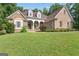 Beautiful brick home featuring a lush green lawn and architectural details including arched entry and dormer windows at 285 Acton Dr, Fayetteville, GA 30215