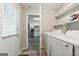 Well-equipped laundry room with modern washer and dryer, shelving, and access to kitchen at 398 Patrick Henry Ct, Riverdale, GA 30274