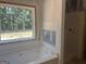 Unfinished bathroom featuring a soaking tub, shower, and a large window, with a view of the outdoors at 5555 Hwy 155 N, Stockbridge, GA 30281