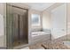 Bright bathroom with a glass-enclosed shower, soaking tub with tile surround, and a window for natural light at 195 Berry Hill Ln, Tyrone, GA 30290