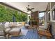 Relaxing covered outdoor patio with a stone fireplace, comfortable seating, and a view of the lush backyard at 195 Berry Hill Ln, Tyrone, GA 30290