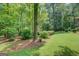 Lush backyard with mature trees and landscaped greenery, providing a serene and private space at 2400 White Pine Ln, Mansfield, GA 30055