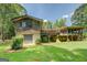 View of the rustic home with unfinished wood exterior and basement garage, complemented by green lawn and mature trees at 2400 White Pine Ln, Mansfield, GA 30055
