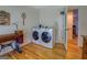 Laundry room with hardwood floors featuring washer, dryer, and sewing machines at 2400 White Pine Ln, Mansfield, GA 30055
